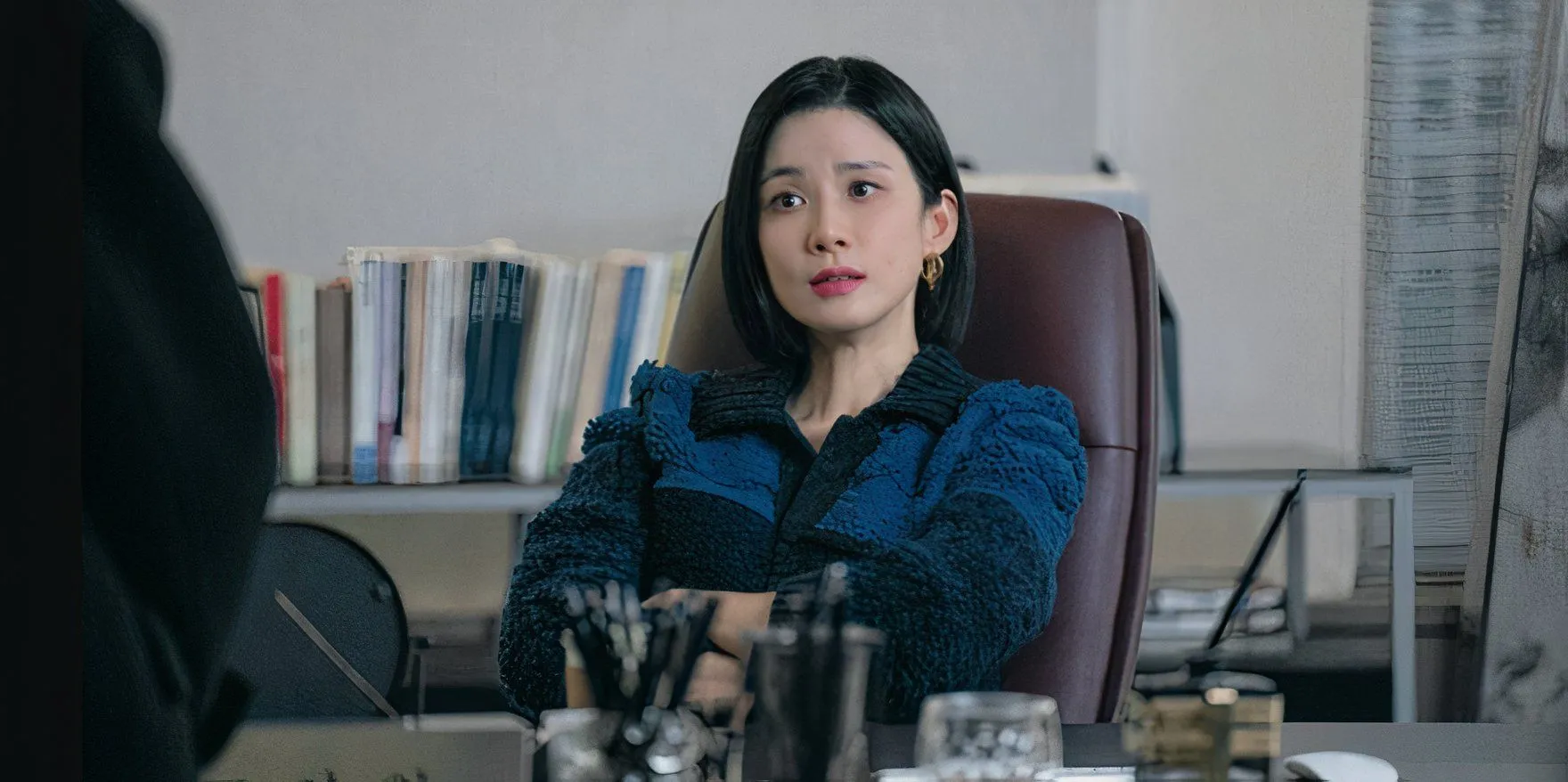 به Ah-in با دستانش روی میزش روی میز بروید، در حالی که با شخصی خارج از صفحه در آژانس K-drama صحبت می کند